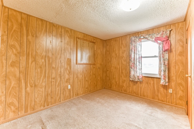 carpeted spare room featuring a textured ceiling and wooden walls