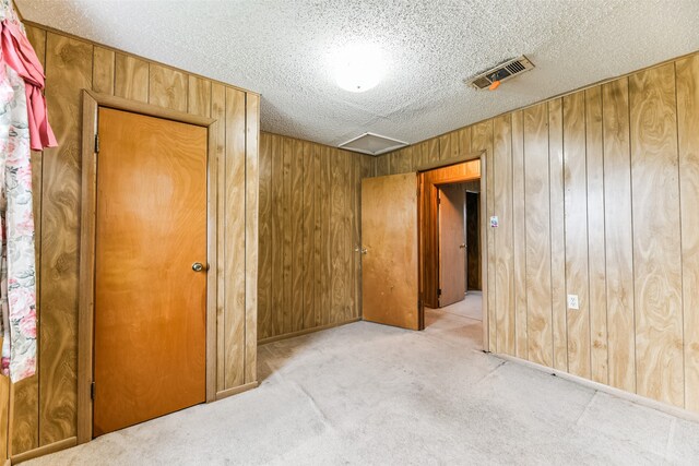 carpeted bedroom featuring a textured ceiling and wooden walls