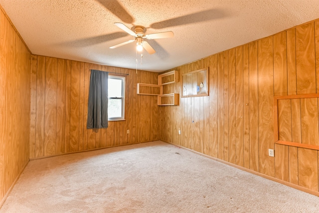 unfurnished room featuring light carpet, a textured ceiling, and wood walls