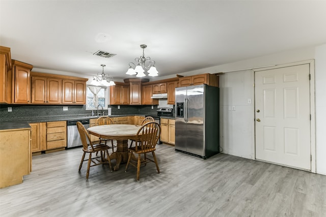 kitchen featuring light hardwood / wood-style flooring, stainless steel appliances, an inviting chandelier, hanging light fixtures, and sink