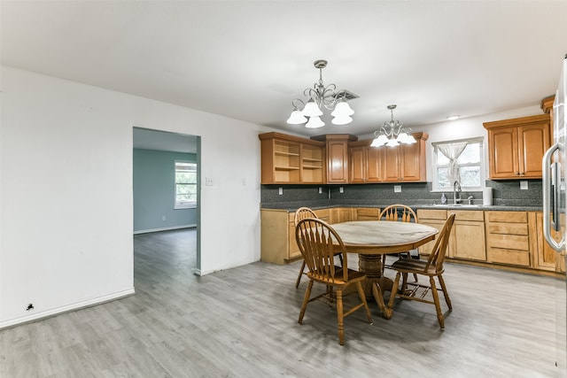 dining room featuring a healthy amount of sunlight, sink, light hardwood / wood-style flooring, and an inviting chandelier