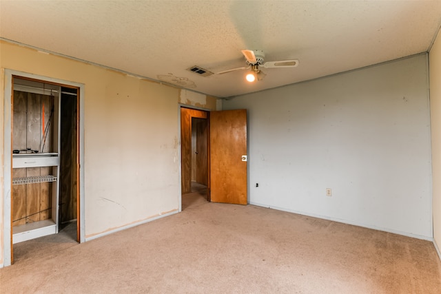 unfurnished bedroom with a textured ceiling, a closet, ceiling fan, and carpet floors