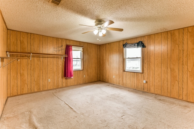 unfurnished room featuring light colored carpet, wooden walls, and ceiling fan