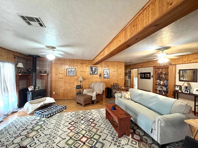 living room featuring a wood stove, a textured ceiling, hardwood / wood-style flooring, and ceiling fan