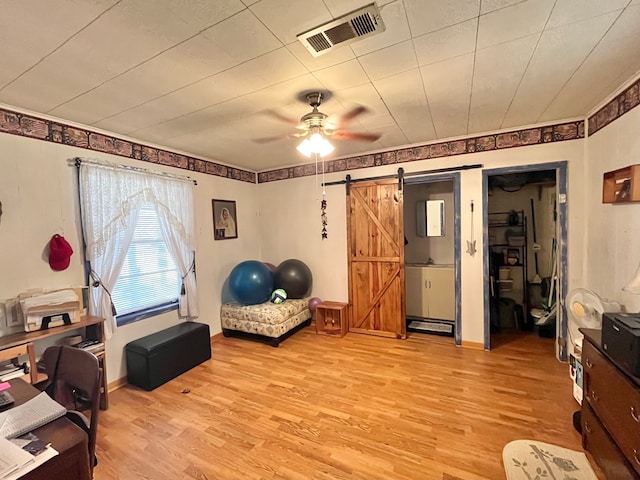 interior space featuring light hardwood / wood-style floors, a barn door, and ceiling fan