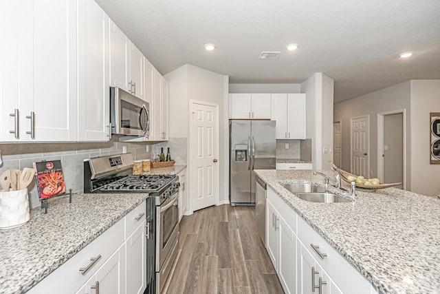 kitchen featuring appliances with stainless steel finishes, tasteful backsplash, sink, white cabinetry, and light stone countertops