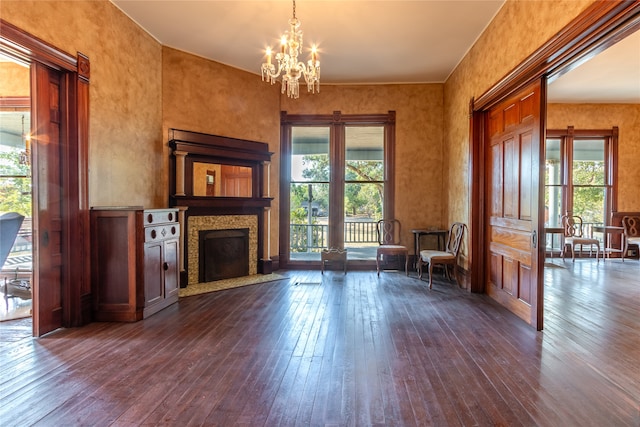 unfurnished living room featuring dark wood-type flooring, an inviting chandelier, and a wealth of natural light