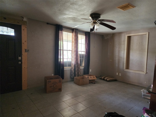 foyer featuring a textured ceiling, ceiling fan, and light tile flooring