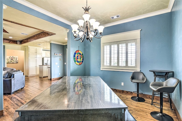 dining area featuring an inviting chandelier, ornamental molding, and hardwood / wood-style flooring