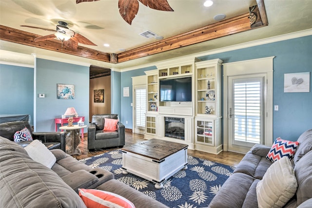 living room with ceiling fan, a raised ceiling, and dark wood-type flooring