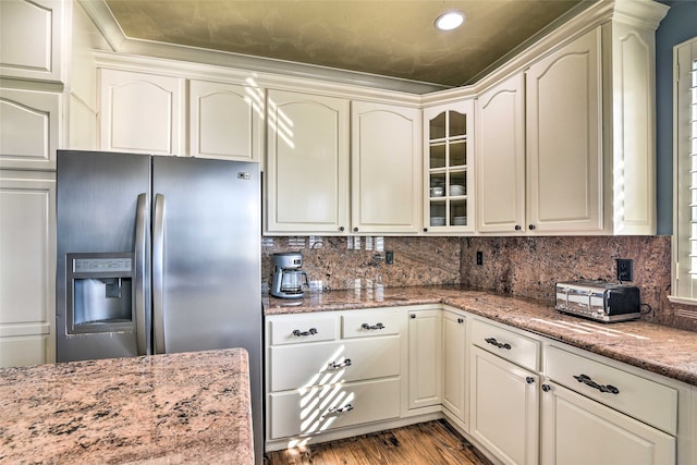 kitchen featuring stainless steel fridge, tasteful backsplash, light wood-type flooring, and light stone counters