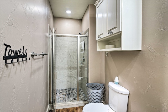 bathroom with toilet, wood-type flooring, and a shower with shower door