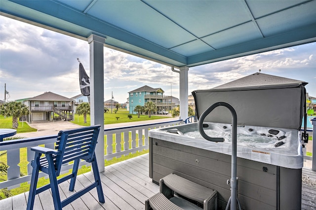 wooden terrace featuring a hot tub and a yard