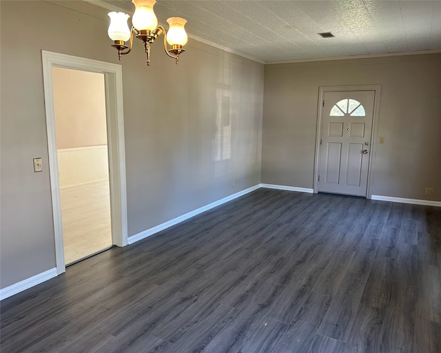 entrance foyer with dark hardwood / wood-style floors, ornamental molding, and a chandelier