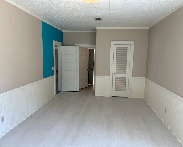 unfurnished bedroom with a closet, light hardwood / wood-style flooring, a textured ceiling, and crown molding