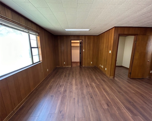 spare room featuring wood walls and dark wood-type flooring