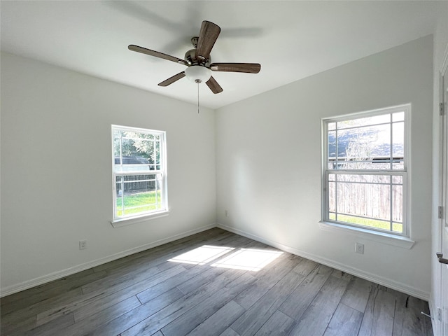 empty room with ceiling fan, dark hardwood / wood-style floors, and plenty of natural light