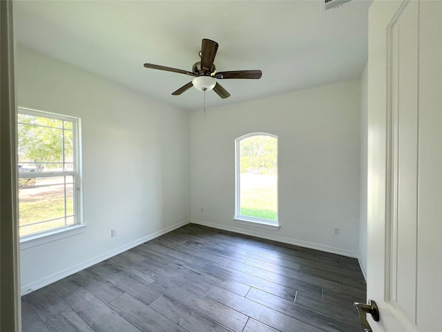 unfurnished room featuring ceiling fan, a wealth of natural light, and dark wood-type flooring