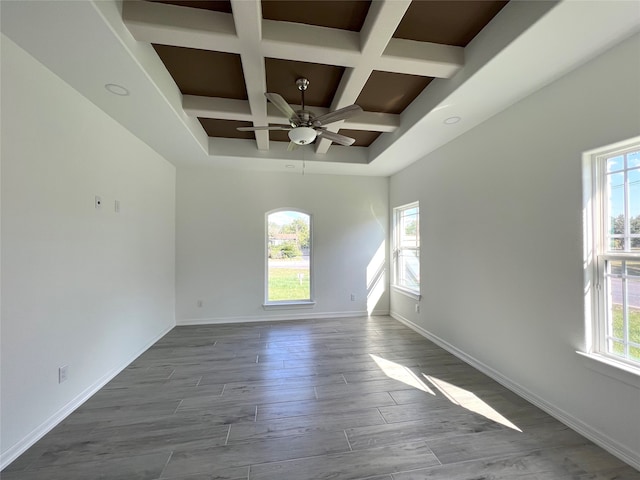 empty room featuring ceiling fan, coffered ceiling, beamed ceiling, and wood-type flooring