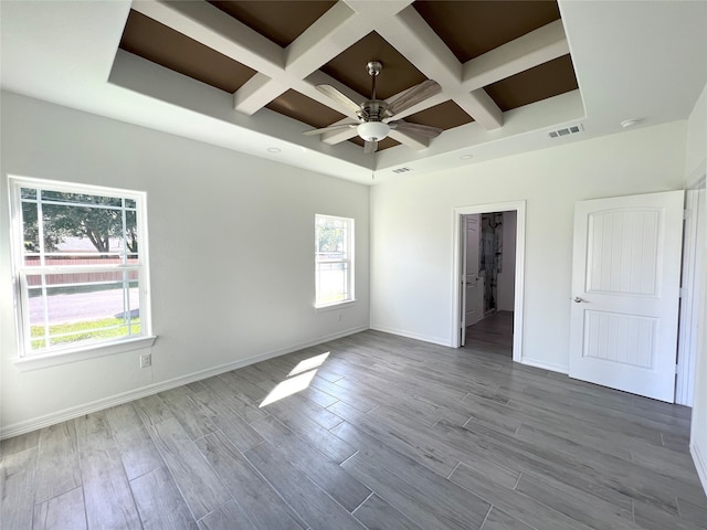 spare room featuring coffered ceiling, beam ceiling, light hardwood / wood-style floors, and ceiling fan