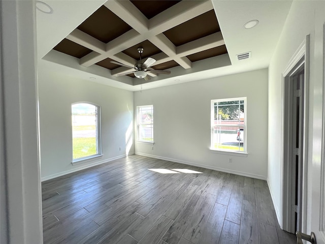 empty room with coffered ceiling, ceiling fan, a wealth of natural light, and beam ceiling