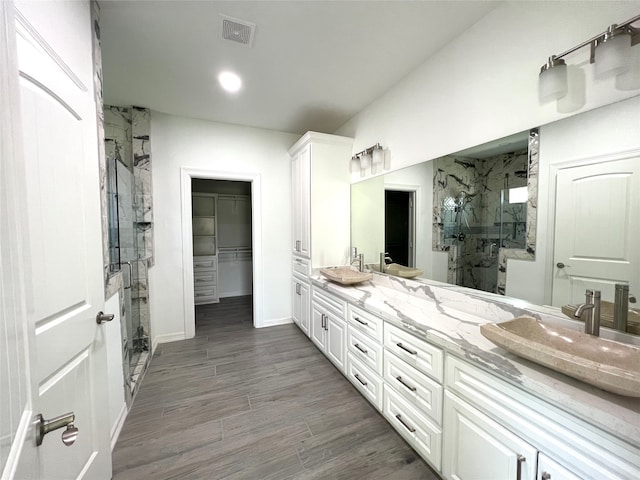 bathroom featuring dual vanity and walk in shower