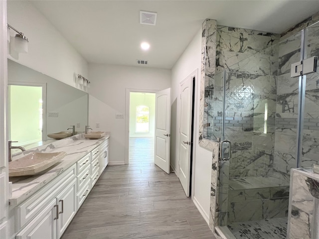 bathroom featuring walk in shower, oversized vanity, dual sinks, and hardwood / wood-style flooring