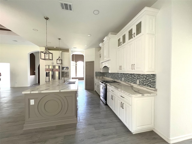 kitchen featuring a kitchen island with sink, light stone counters, hanging light fixtures, stainless steel electric range oven, and white cabinetry