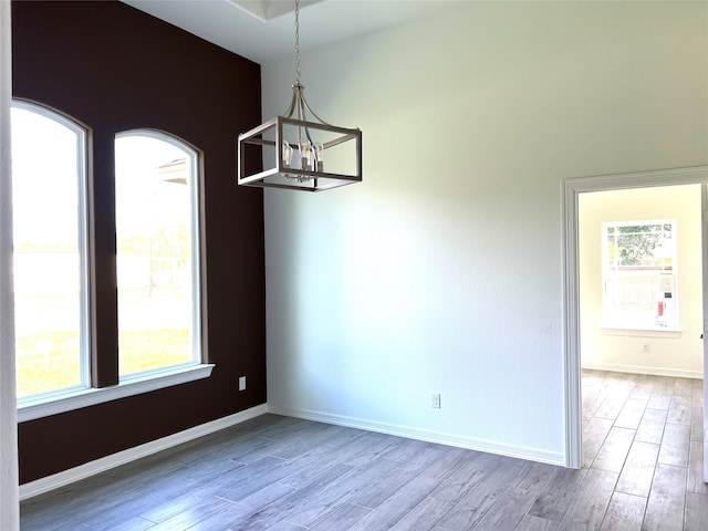 unfurnished dining area with light wood-type flooring and an inviting chandelier