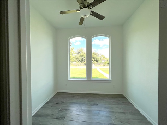 empty room with ceiling fan, a wealth of natural light, and dark wood-type flooring