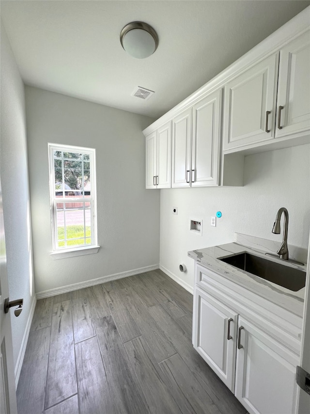 washroom featuring cabinets, hookup for an electric dryer, light hardwood / wood-style floors, and sink