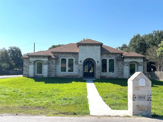 mediterranean / spanish home featuring a front yard and french doors