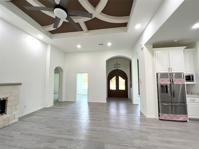 interior space featuring ceiling fan, a raised ceiling, light hardwood / wood-style flooring, coffered ceiling, and a fireplace