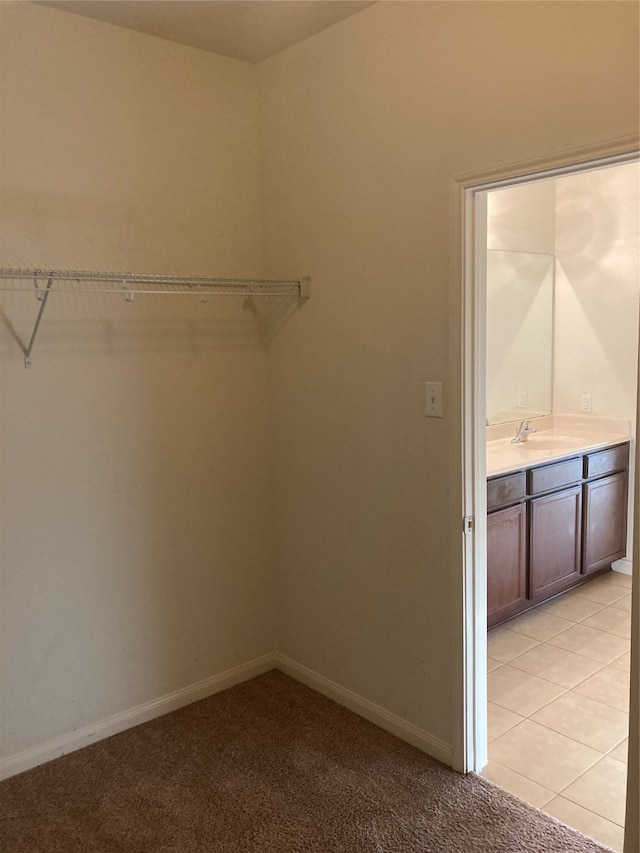 walk in closet with light tile flooring and sink