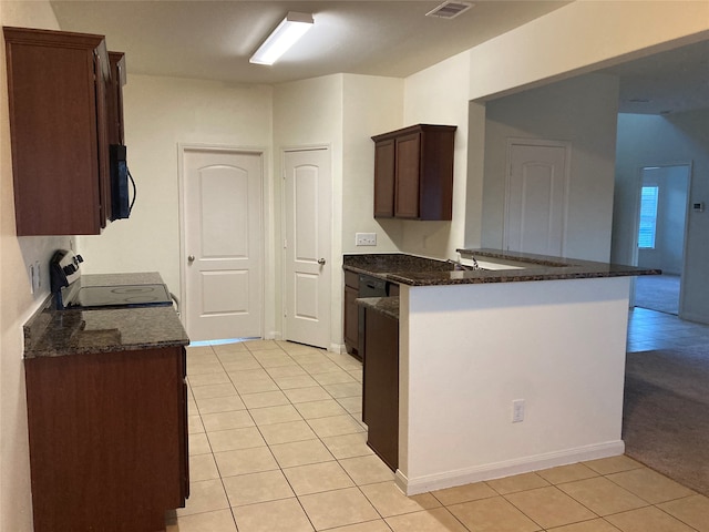 kitchen featuring dark stone counters, range with electric cooktop, and light tile floors