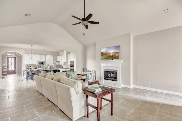 tiled living room featuring ceiling fan and high vaulted ceiling