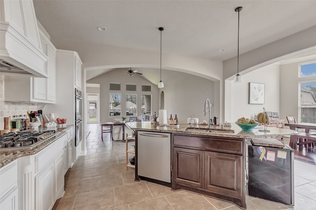 kitchen with ceiling fan, sink, white cabinets, light stone countertops, and custom exhaust hood