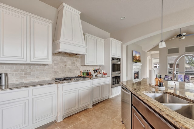 kitchen featuring appliances with stainless steel finishes, custom range hood, pendant lighting, ceiling fan, and vaulted ceiling