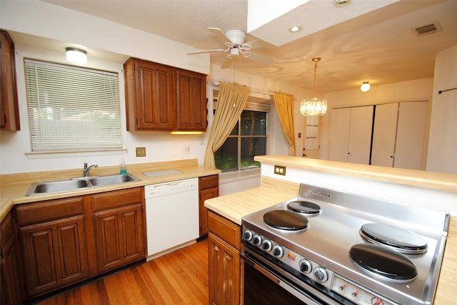 kitchen with light wood-type flooring, range, ceiling fan with notable chandelier, sink, and white dishwasher