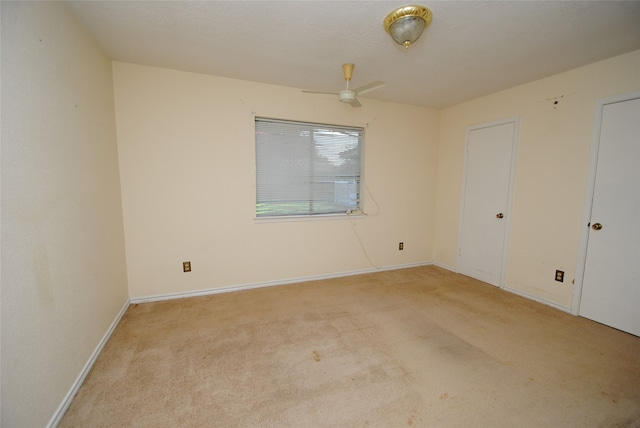 empty room featuring ceiling fan and light carpet