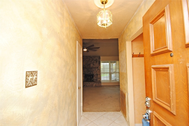 corridor with a notable chandelier, light tile floors, and a textured ceiling