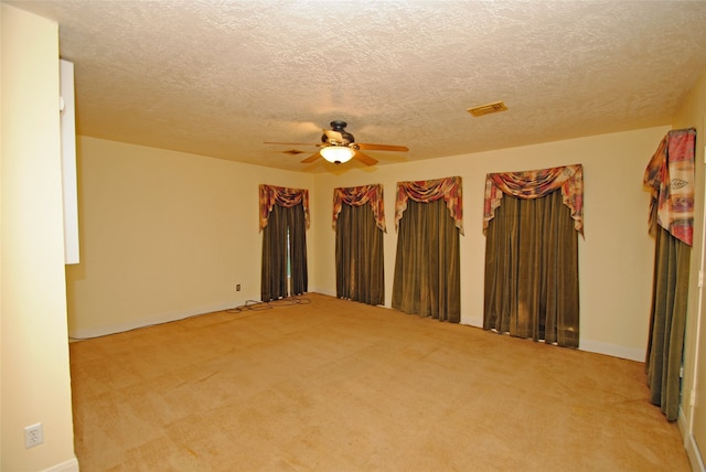 unfurnished room featuring light carpet, ceiling fan, and a textured ceiling