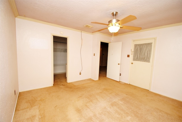 unfurnished bedroom featuring ceiling fan, a walk in closet, ornamental molding, light carpet, and a closet