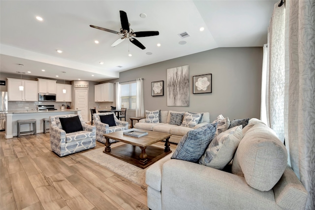 living room featuring ceiling fan, vaulted ceiling, and light wood-type flooring