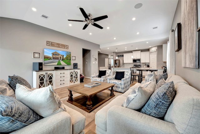 living room featuring vaulted ceiling, ceiling fan, and light hardwood / wood-style floors