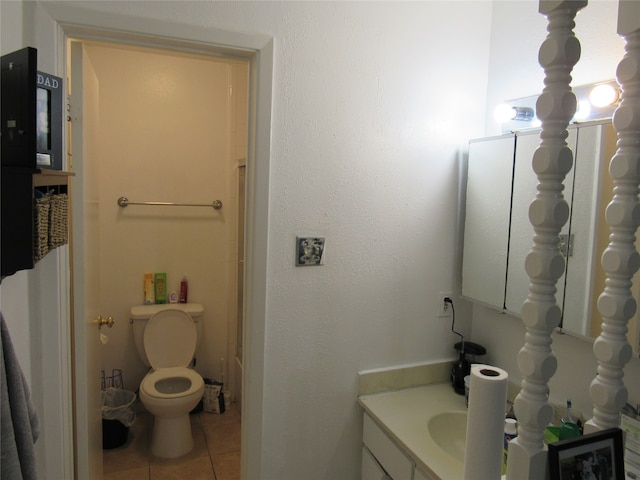 bathroom featuring toilet, tile flooring, and vanity