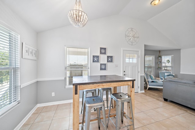 dining room with a chandelier, light tile flooring, and vaulted ceiling