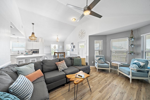 living room featuring ceiling fan, light wood-type flooring, high vaulted ceiling, and a wealth of natural light