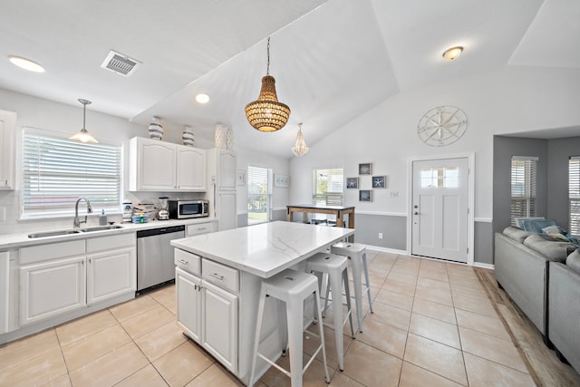 kitchen with lofted ceiling, hanging light fixtures, sink, stainless steel appliances, and a kitchen island