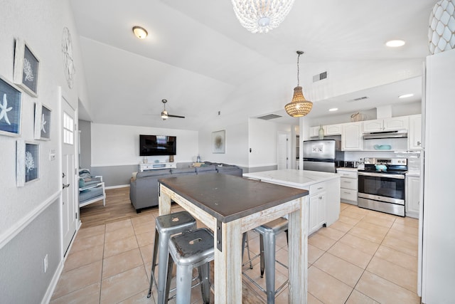 kitchen featuring appliances with stainless steel finishes, a kitchen bar, decorative light fixtures, ceiling fan with notable chandelier, and white cabinetry